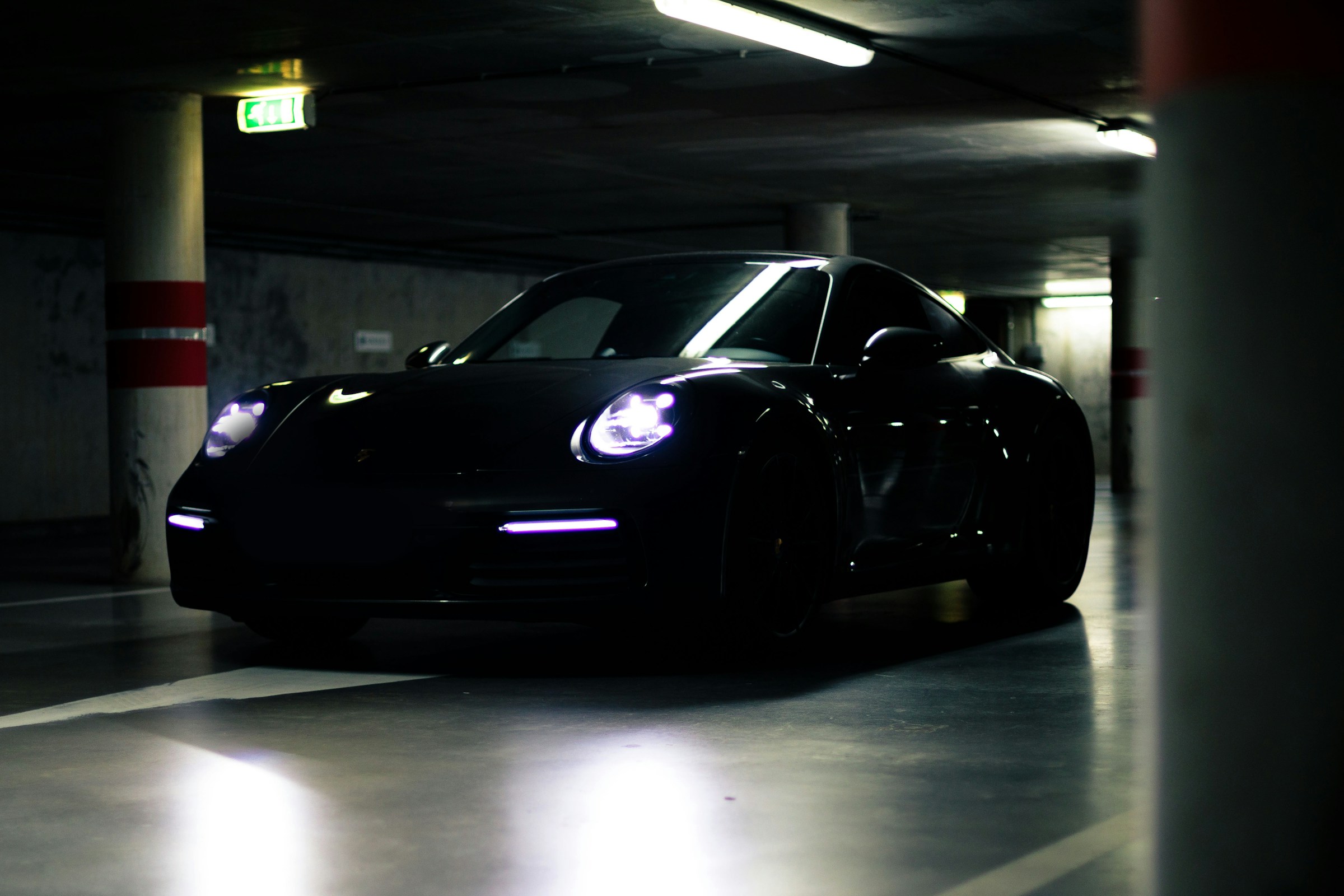 Black sports car in a shadowy concrete garage